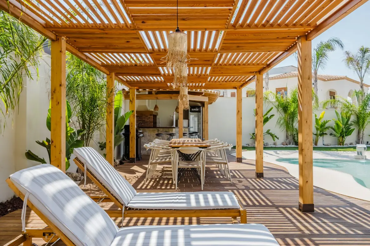 Espace extérieur avec pergola créant de l'ombre et éclairage tamisé en soirée