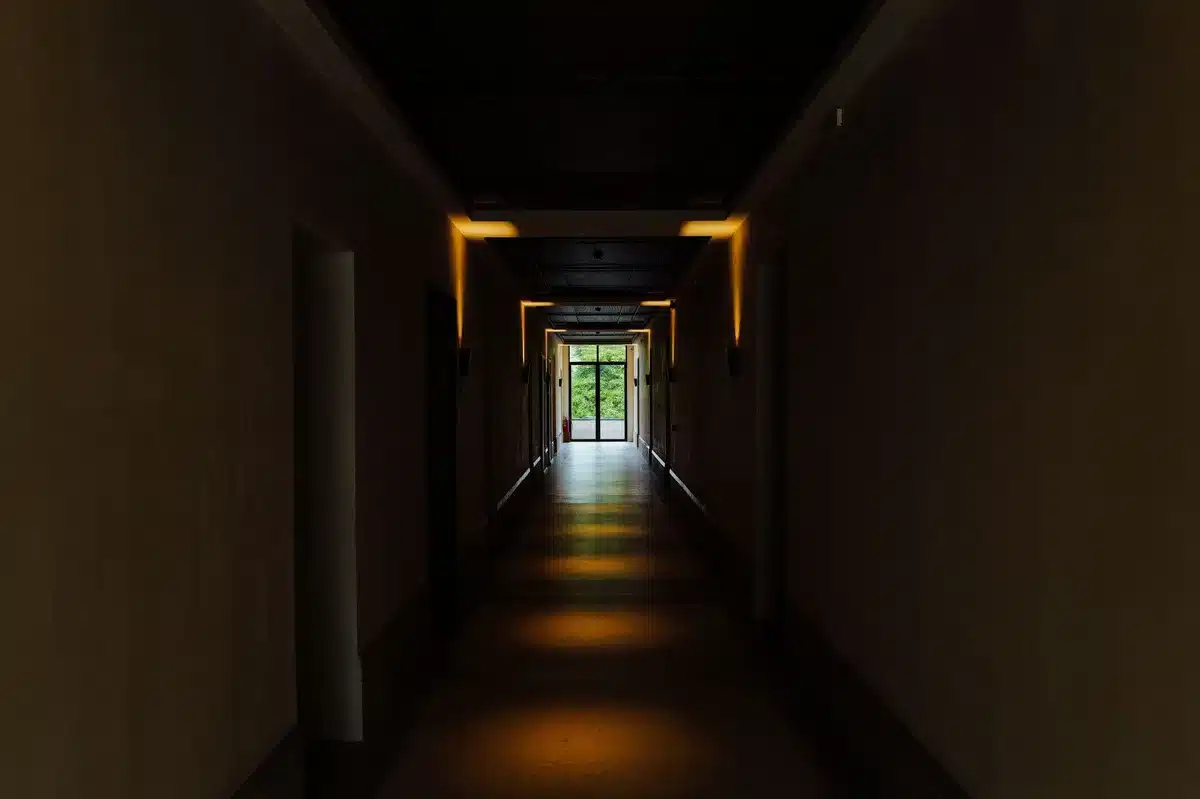 Un couloir central sombre illuminé par la lumière naturelle diffusée depuis le plafond, rendant l'espace plus accueillan