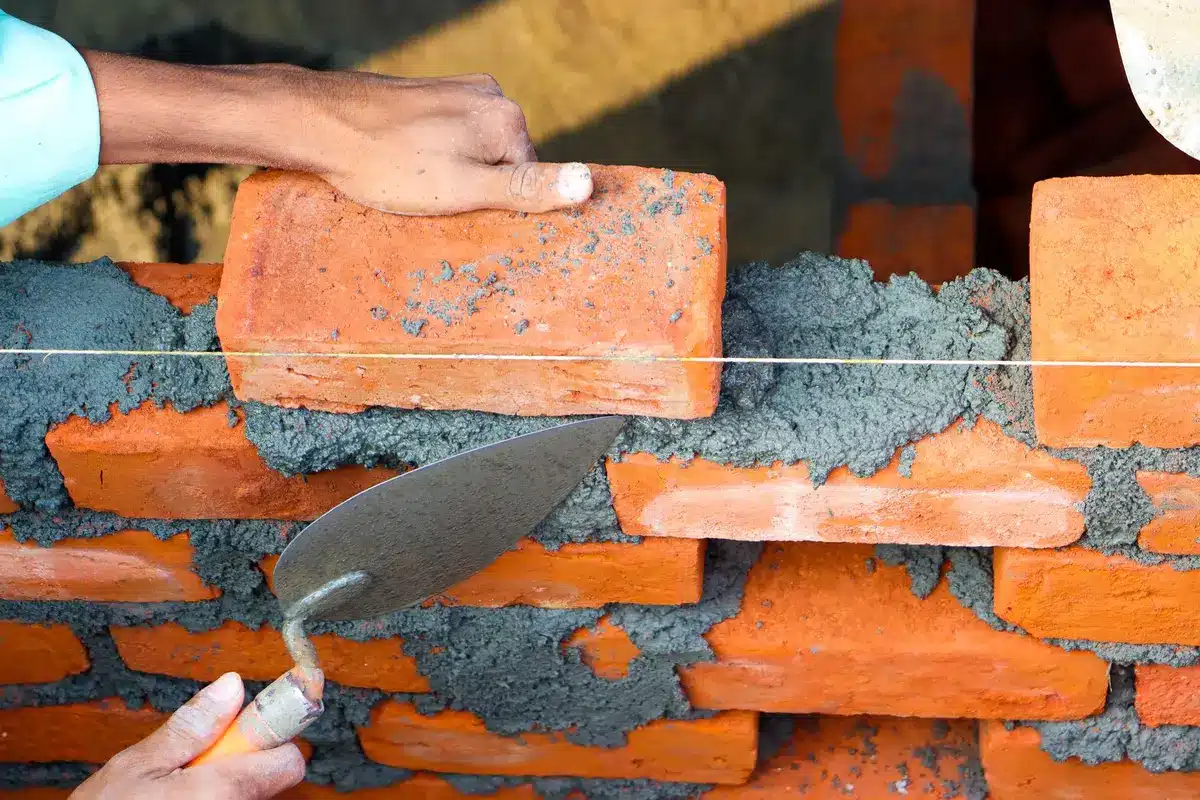 Maçon en train de poser des pierres avec du mortier sur un mur en construction