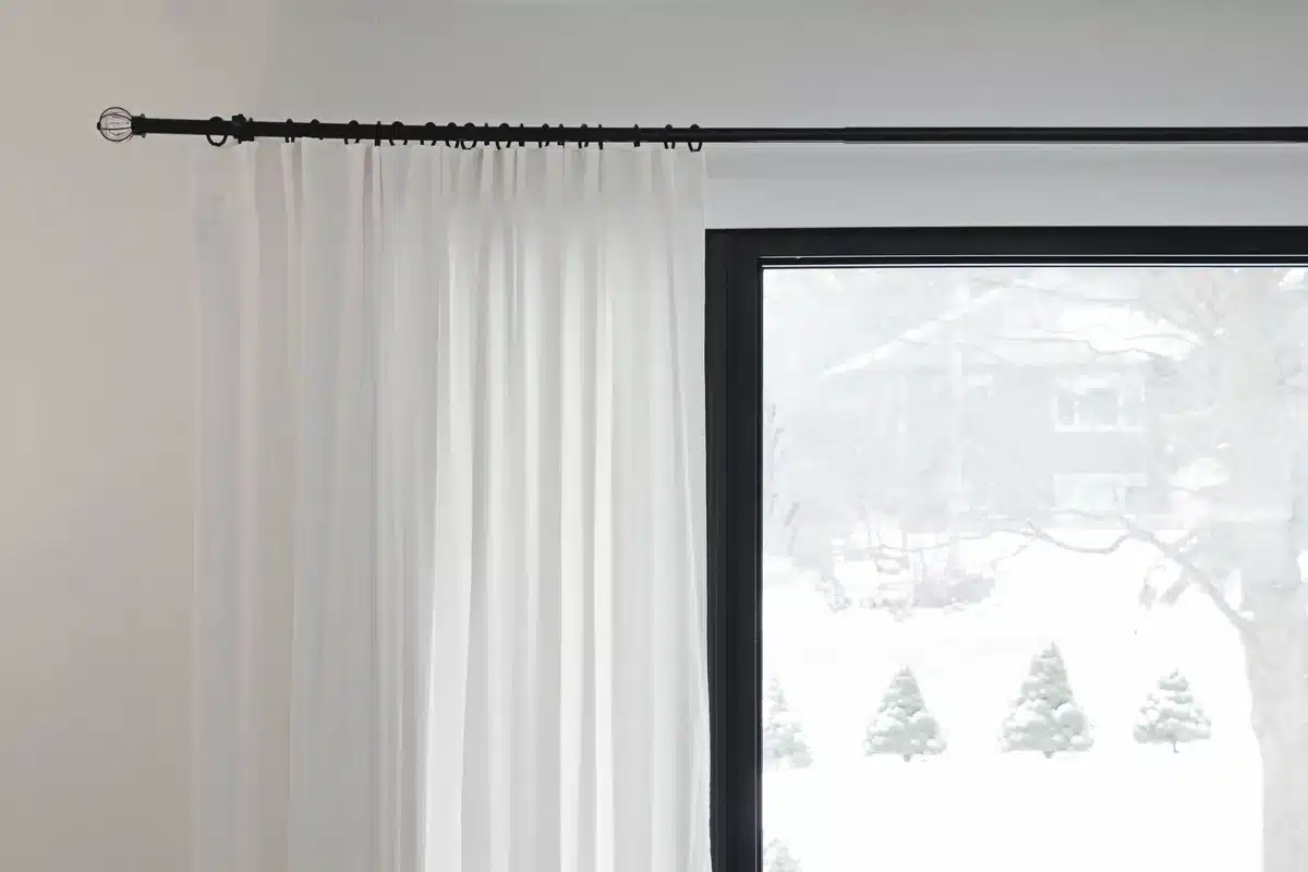 Rideau suspendu près du plafond avec tringle qui dépasse de la fenêtre pour agrandir visuellement la pièce