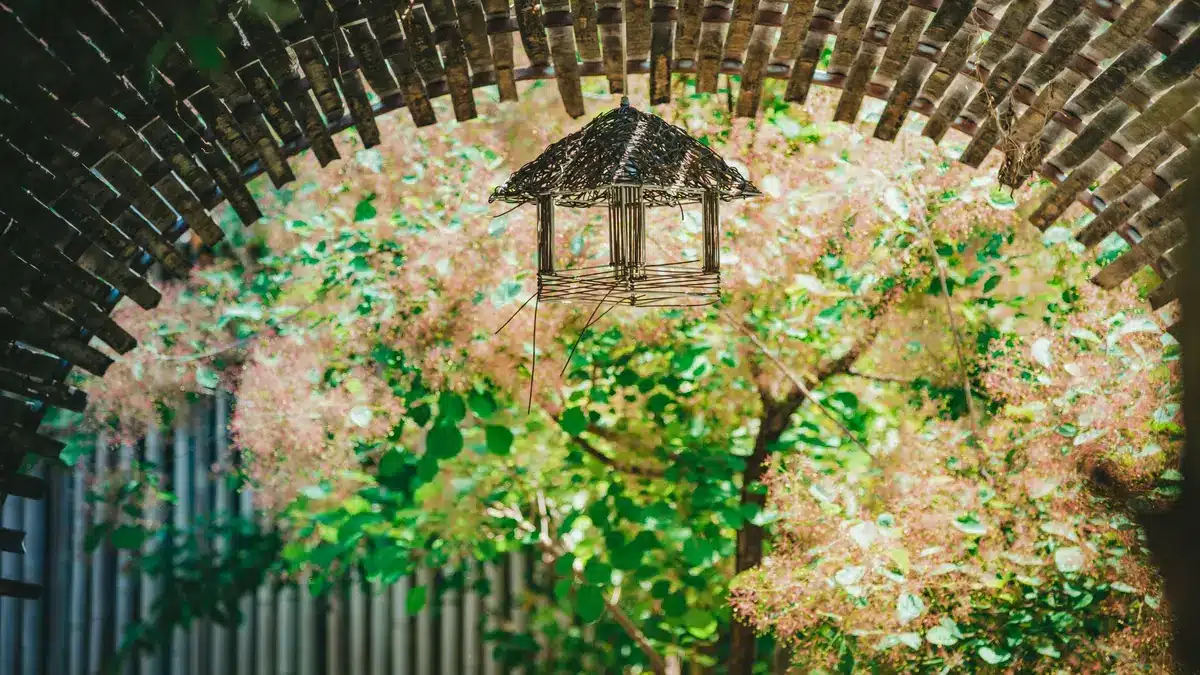 Matériaux variés pour une arche de jardin : bois de noisetier, châtaignier et fer.