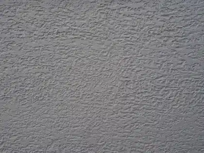 Main lissant une finition en stuc décoratif sur un mur, montrant la texture et le rendu satiné.