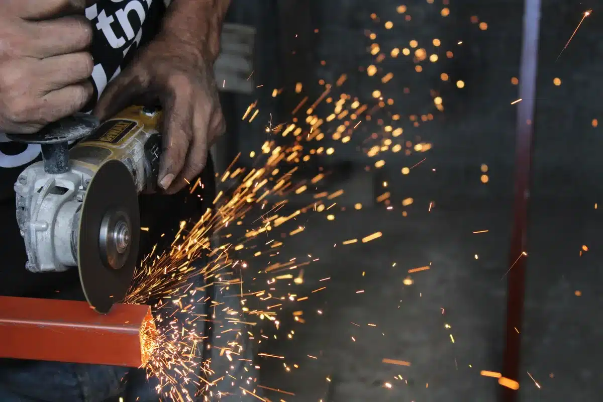 Outils de découpe de briques : meuleuse d'angle, ciseau et massette sur établi