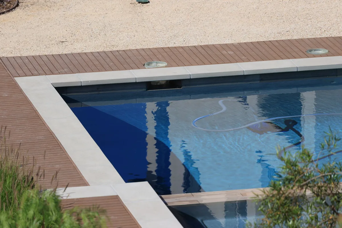 Terrasse autour d'une piscine avec accès de circulation et local technique compact