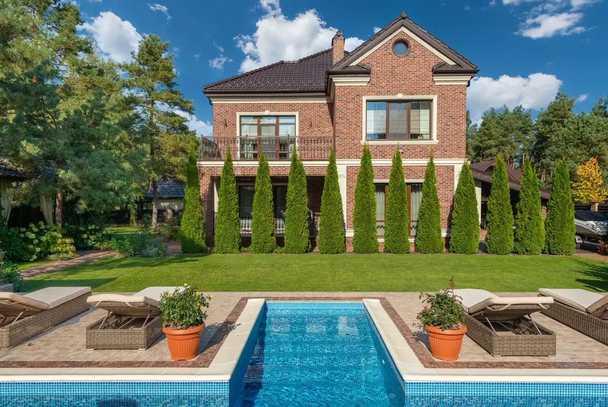 Une petite piscine rectangulaire installée dans un petit jardin avec terrasse et plantes