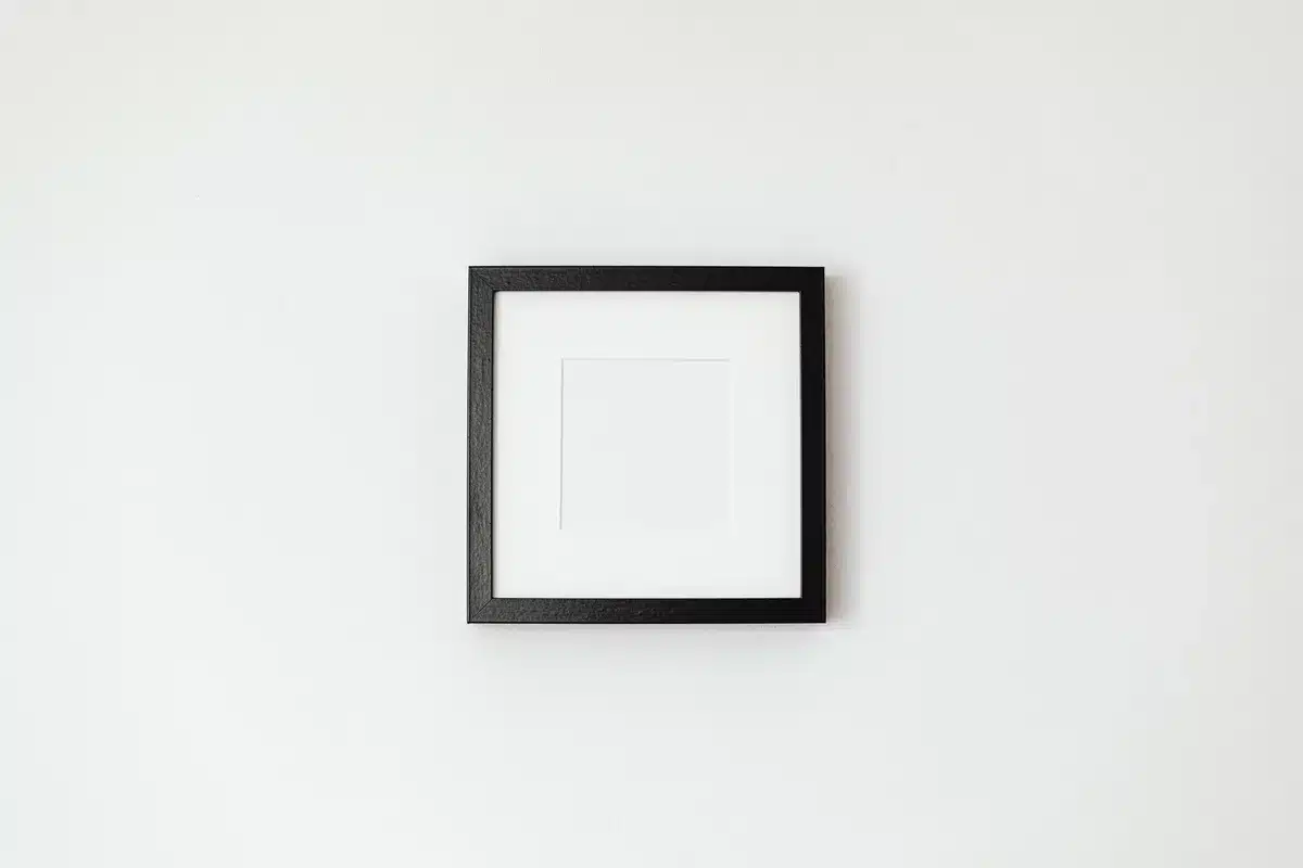 Gabarits en papier fixés sur un mur blanc pour visualiser l'agencement des cadres avant accrochage