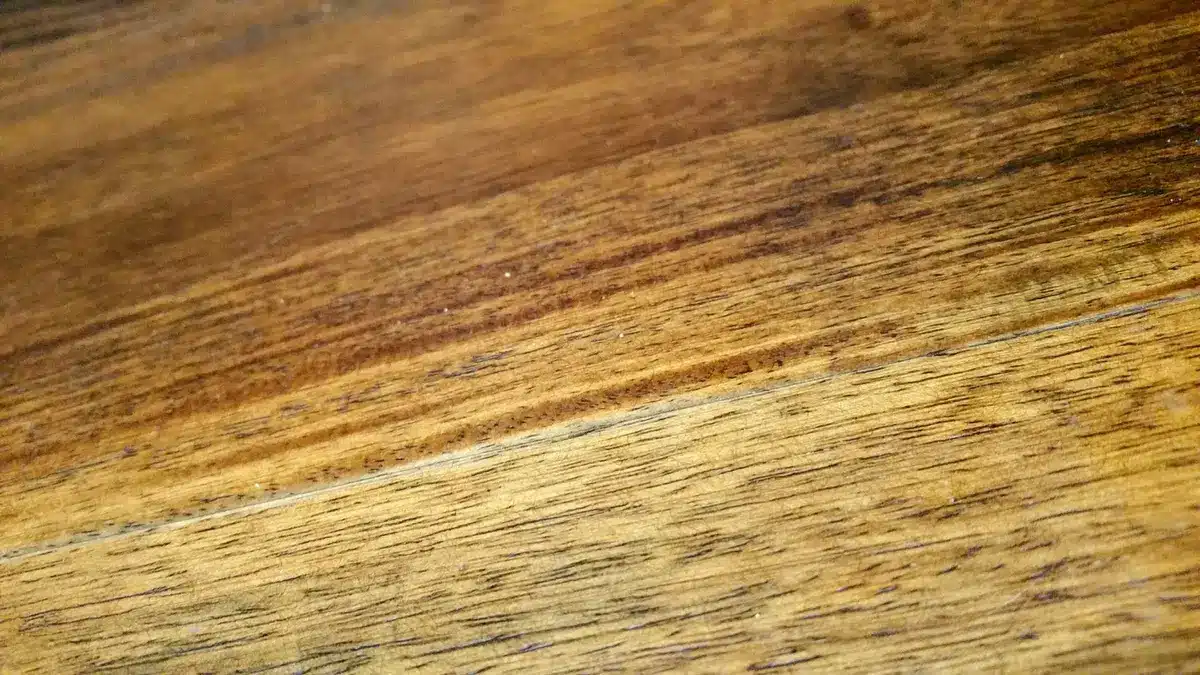 Cale en bois glissée sous une lame de parquet pour combler un vide