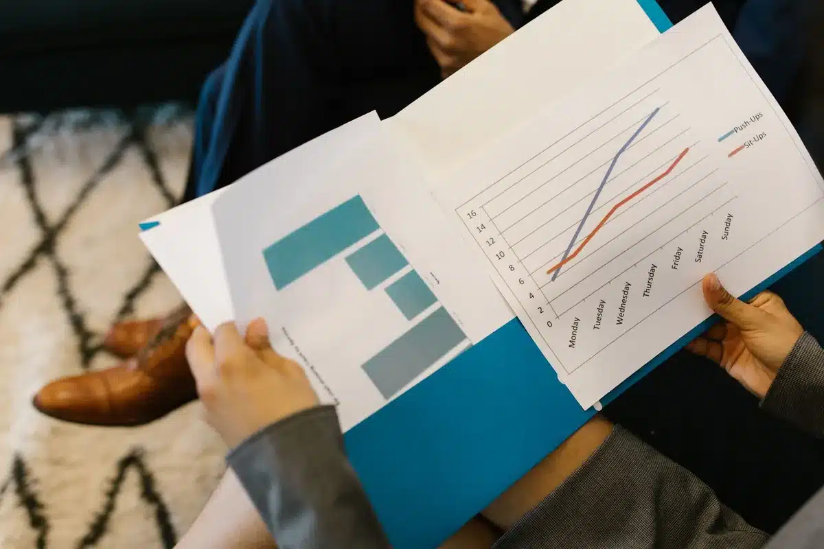 Documents d'investissement et graphiques de suivi étalés sur un bureau pour un bilan périodique