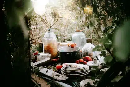 Mains versant des épluchures et des feuilles mortes dans un bac à compost en bois dans un jardin