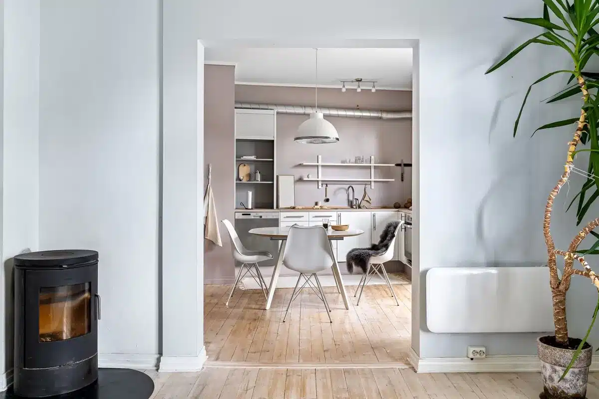 Une cheminée ancienne en pierre avec un fauteuil design contemporain devant elle.