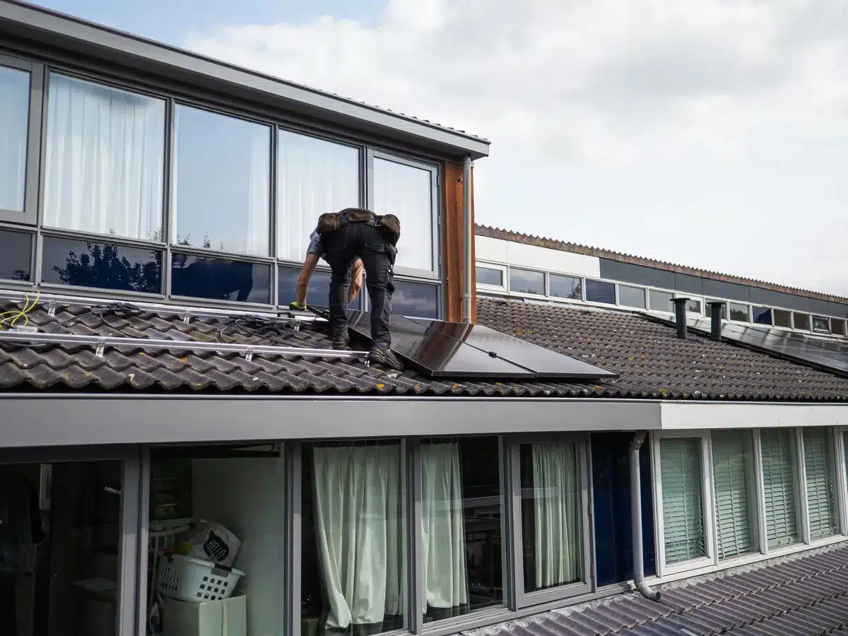 Technicien mesurant et dimensionnant une installation de panneaux solaires sur un toit.