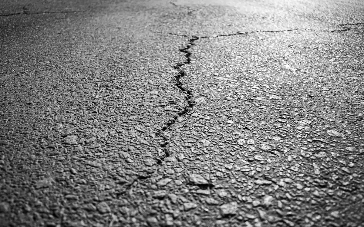 Allée en enrobé présentant des fissures dues à une mauvaise préparation