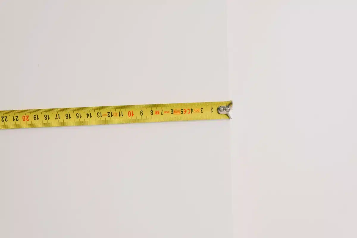 Mesure de la hauteur d'une pièce avec un mètre ruban pour calculer la surface à peindre
