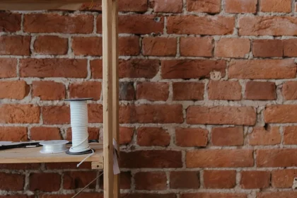 Intérieur minimaliste de style atelier avec étagères en bois brut, sol en béton et rangements ouverts.