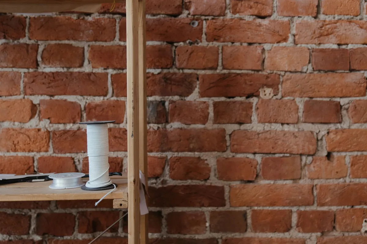 Intérieur minimaliste de style atelier avec étagères en bois brut, sol en béton et rangements ouverts.