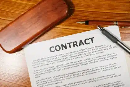 Mains tenant un contrat endommagé près d'outils de construction, symbolisant un litige de malfaçon