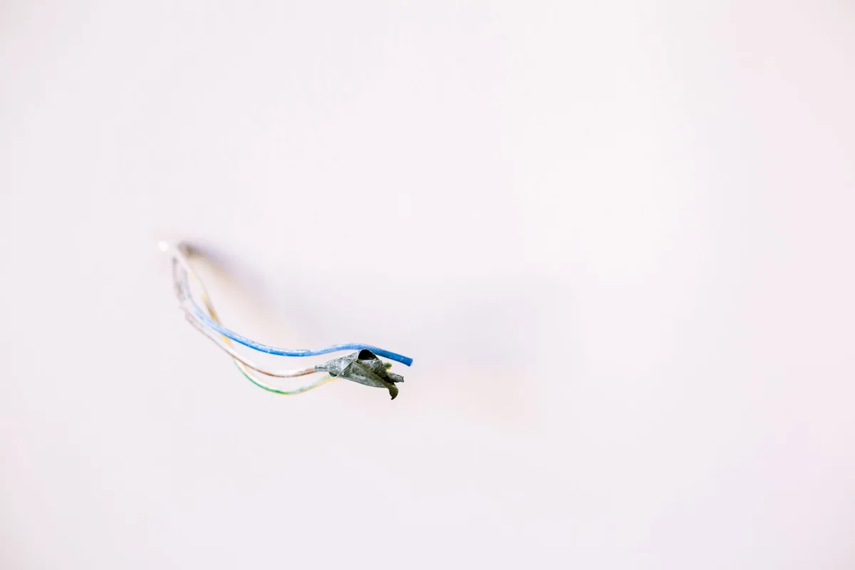 Anciens fils électriques visibles et vétustes dans une installation non conforme