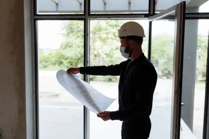 Gros plan sur une main tenant un devis ou blueprint électrique avec des symboles de sécurité visibles