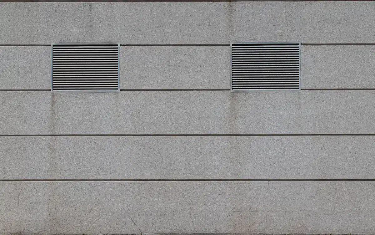 Grilles d'aération placées sur des côtés opposés d'un vide sanitaire pour circulation d'air