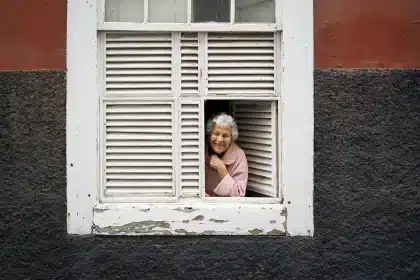 Balcon urbain avec volets mi-clos et plantes sous forte chaleur