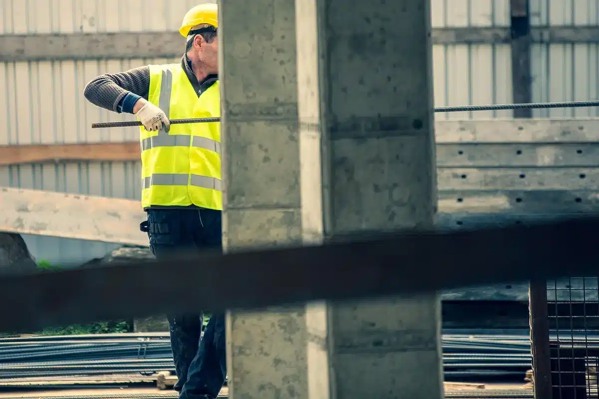 Mur de parpaings partiellement monté sur un chantier en plein jour, mains gantées et truelle