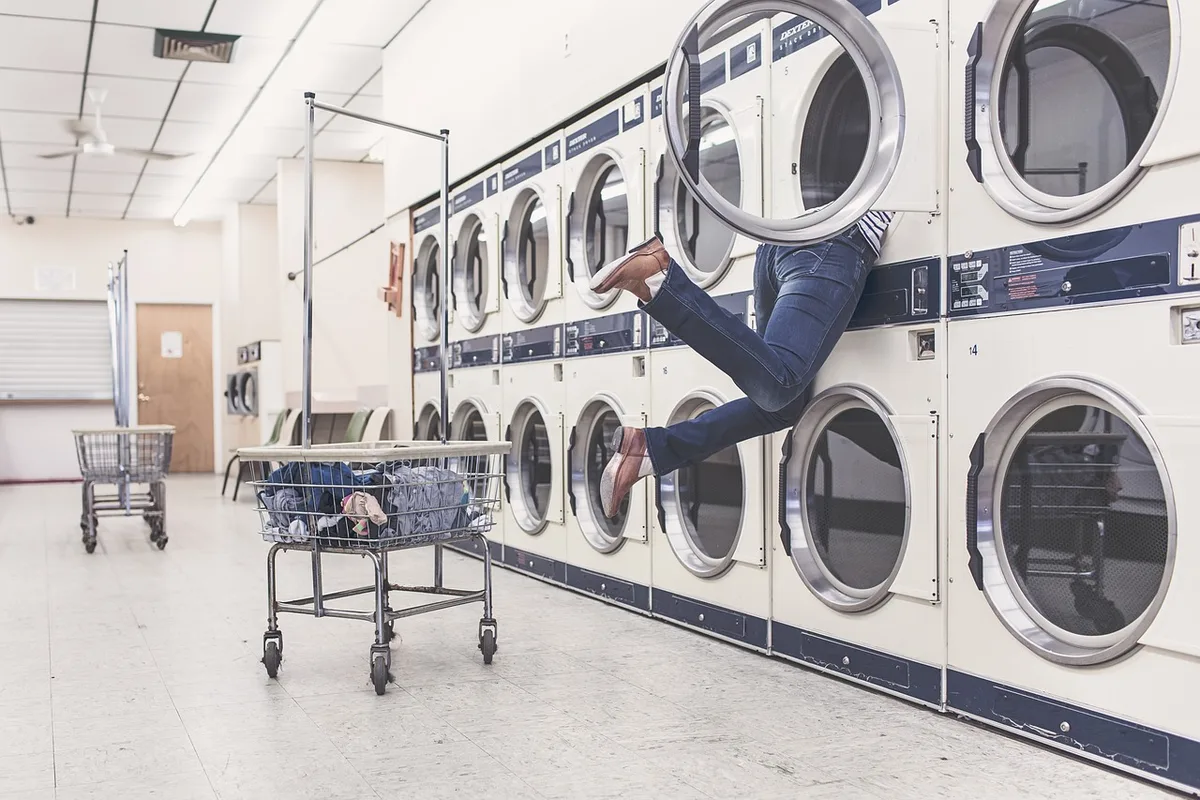 Lave-linge et sèche-linge placés côte à côte avec plan de travail pour le tri du linge