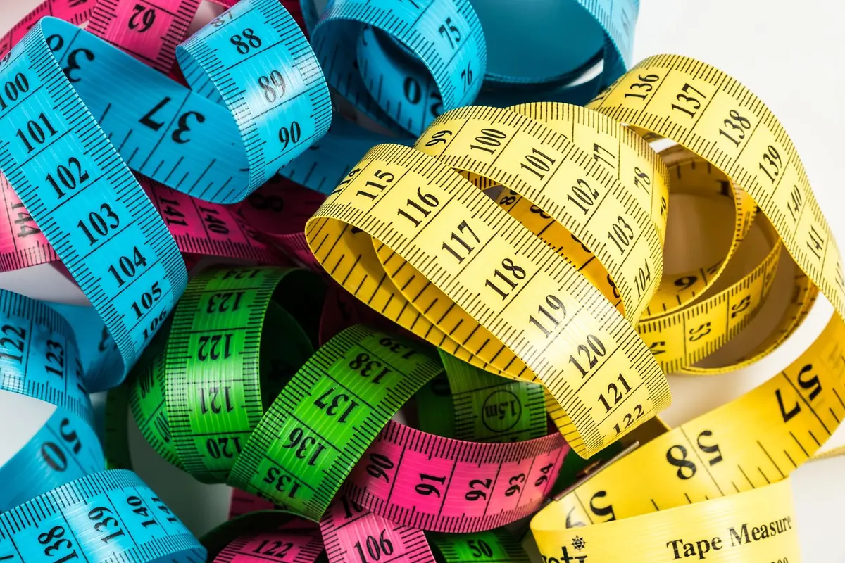 Mesures et échantillons de tissu posés sur un canapé pour choisir une housse adaptée
