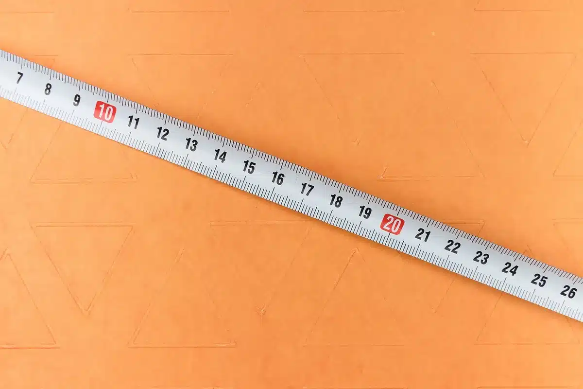 Ruban à mesurer et plan posé sur un sol d'appartement montrant m² calculés