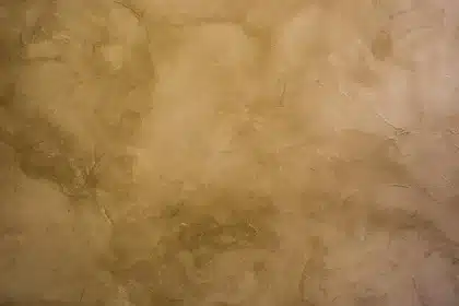 Atelier lumineux avec mur en stucco partiellement lissé et outils posés près d'une fenêtre