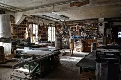 Panneaux de contreplaqué empilés et mains gantées sur un plan de coupe dans un atelier