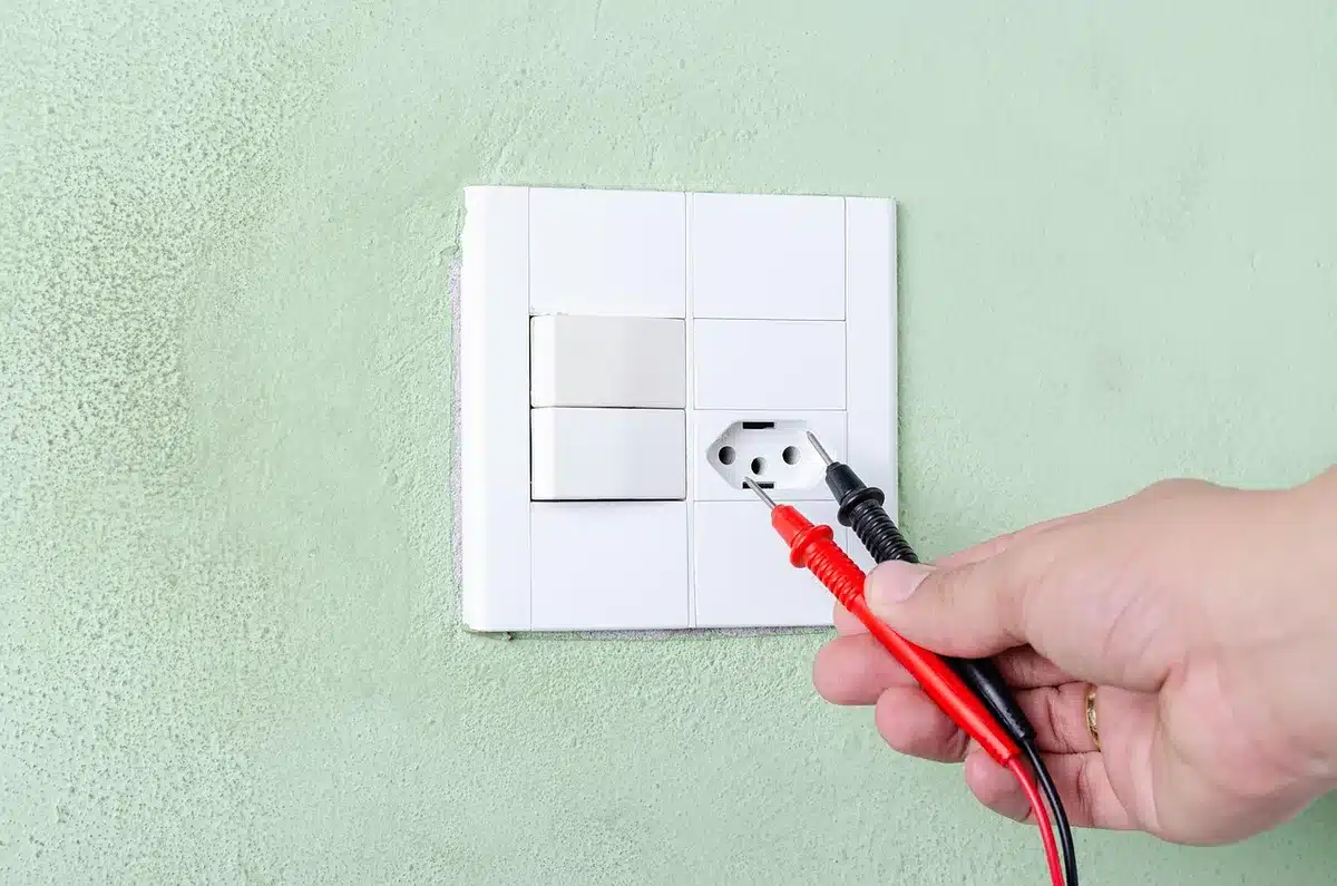 Personne observant une chambre vide avec fenêtres et prises pour planifier l'aménagement