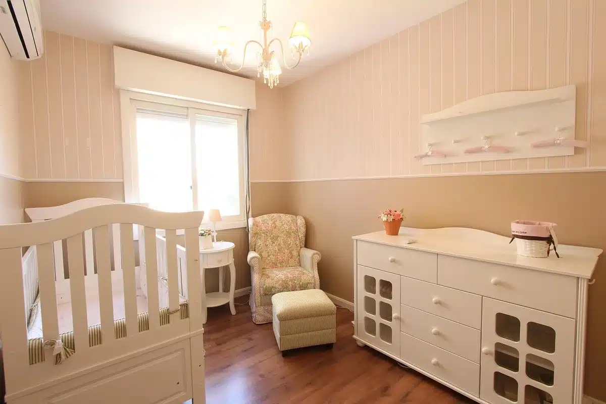 Coin de chambre de bébé en journée avec un lit, commode et humidificateur près d'une fenêtre