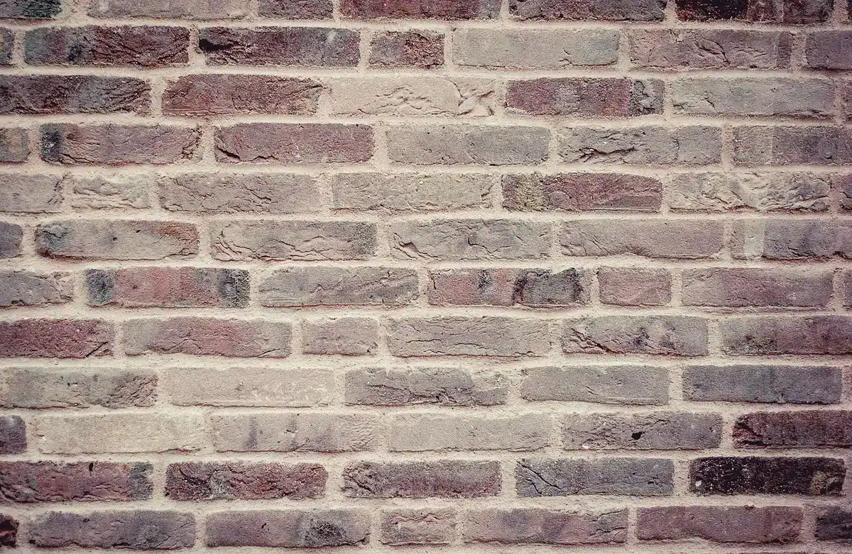 Personne préparant un mur avec ponçage et rebouchage avant peinture