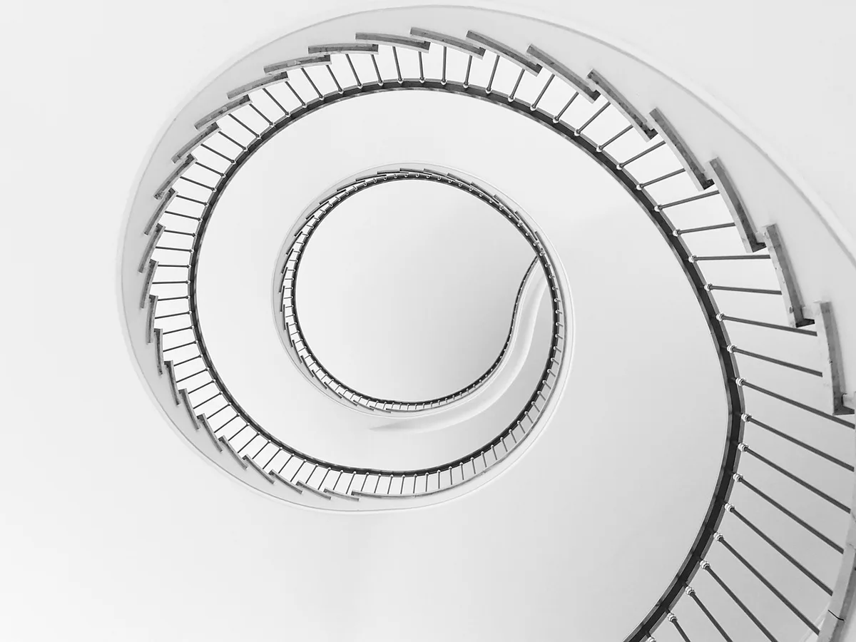 Cage d'escalier lumineuse avec lustre suspendu valorisant la verticalité